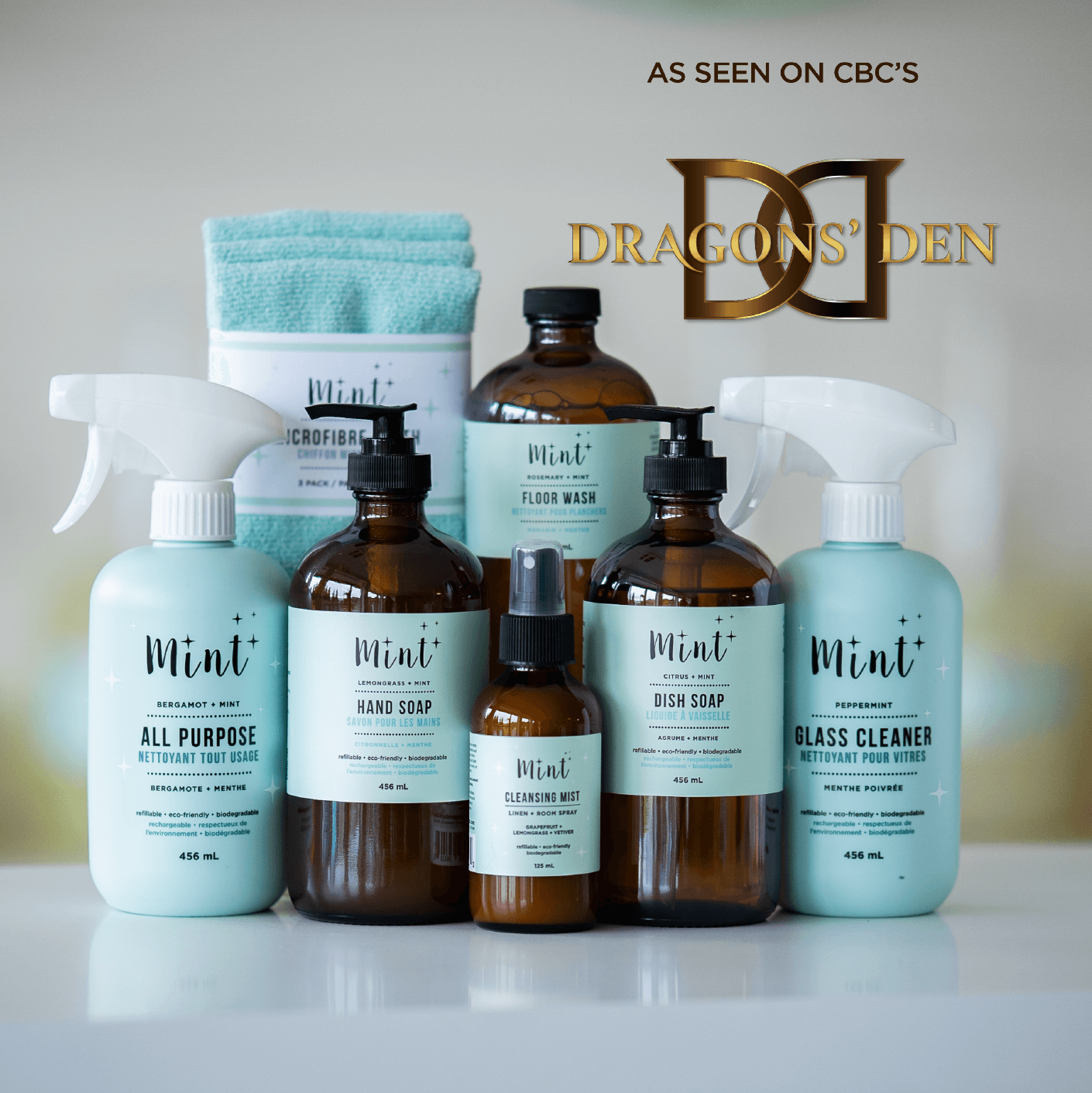 A collection of Mint Cleaning Products, including hand soap, dish soap, all-purpose cleaner, glass cleaner, floor wash, cleansing mist, and microfiber cloths. The image features a &quot;As seen on CBC&